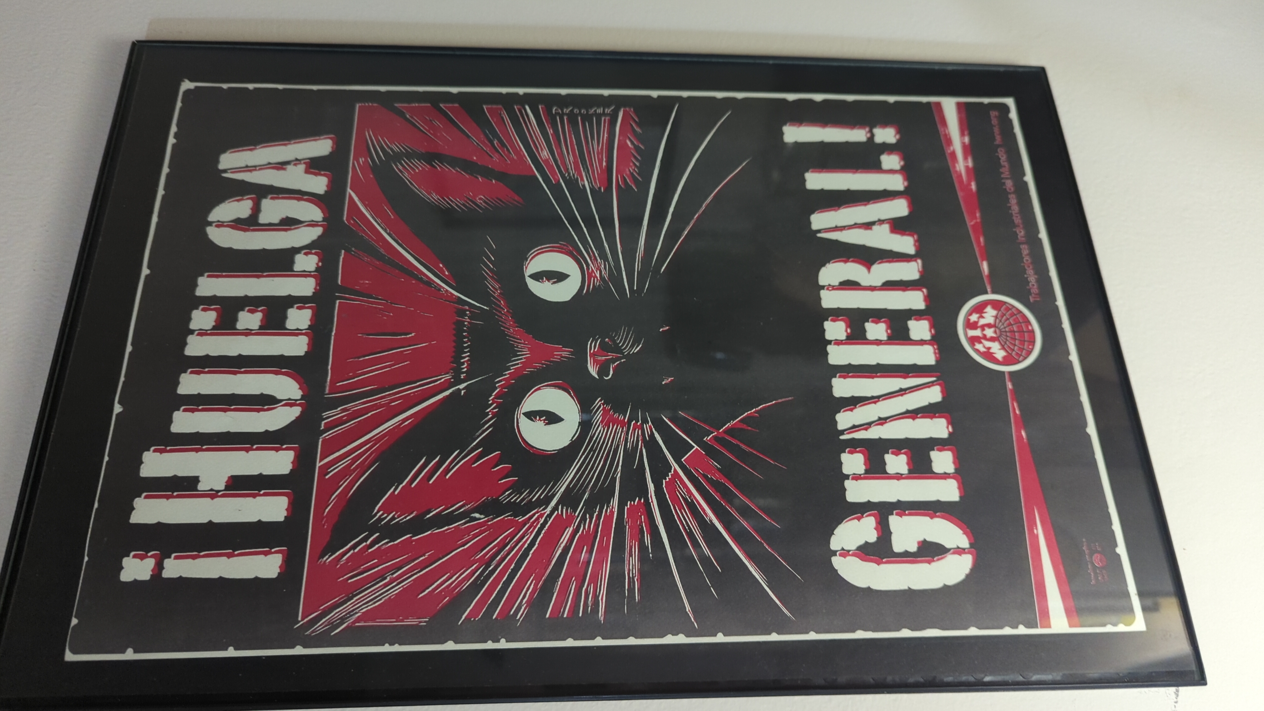 A framed IWW poster featuring the cat sabo-tabby, and the text ¡Huelga General! or "General Strike" in English.