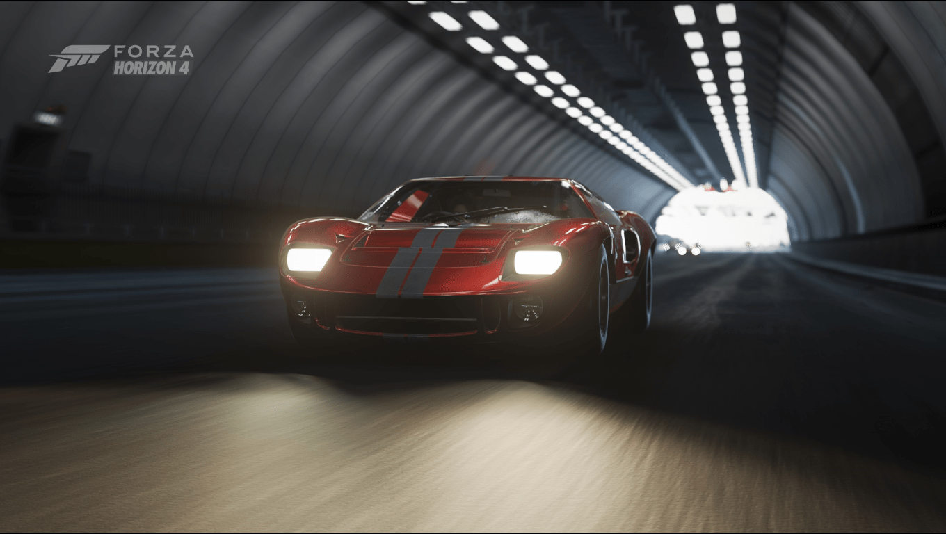 A screenshot of the front side of a Ford GT40 with headlights turned on driving in a dark tunnel